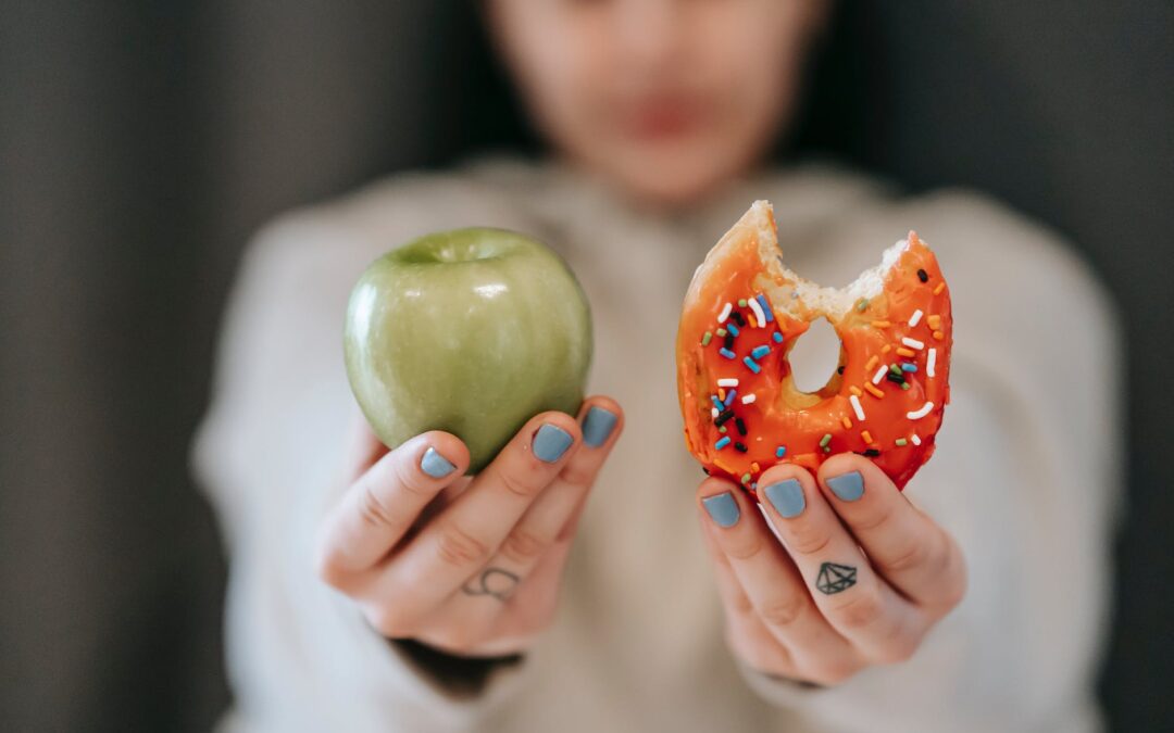 woman showing apple and bitten doughnut