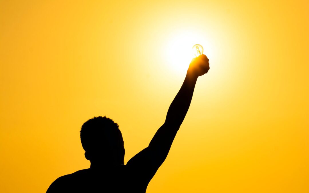 man with light bulb against sunset sky