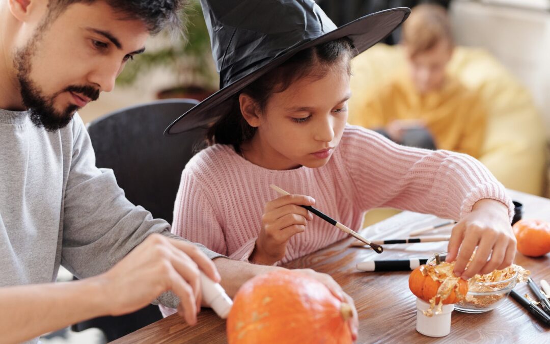 father and daughter decorating pumpkins for halloween
