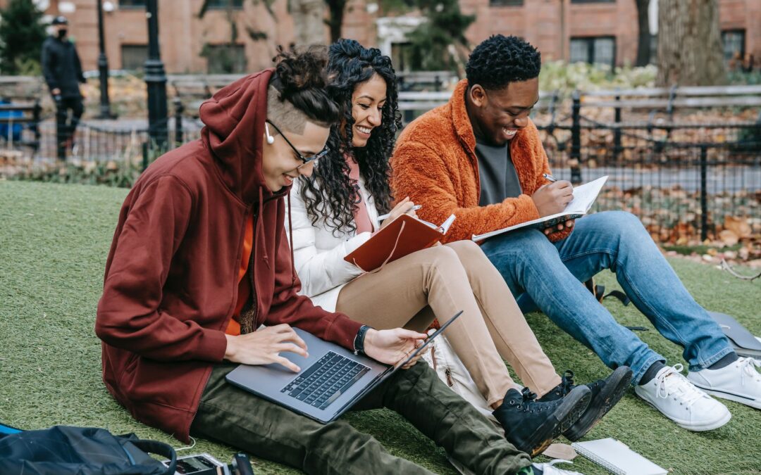 cheerful diverse classmates studying in park