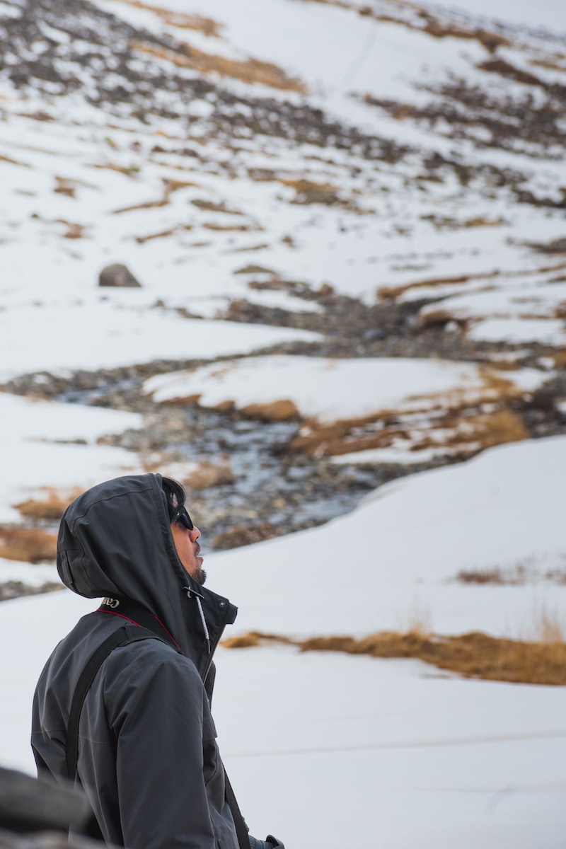 person in black hoodie standing on snow covered ground during daytime
