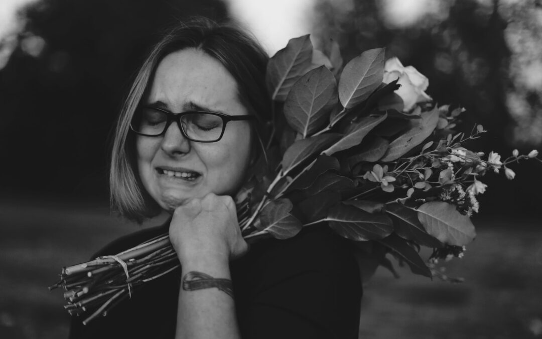 grayscale photo of crying woman holding bouquet of flowers