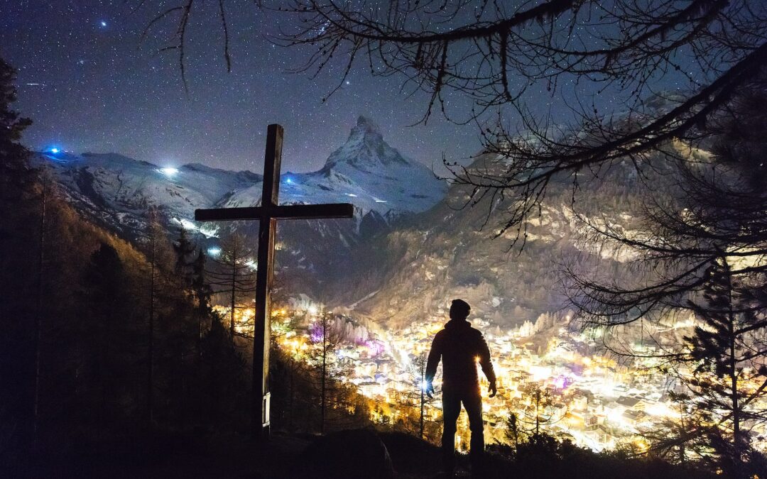 man standing near cross during night