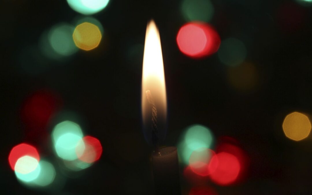 A candle flame burns between a bokeh